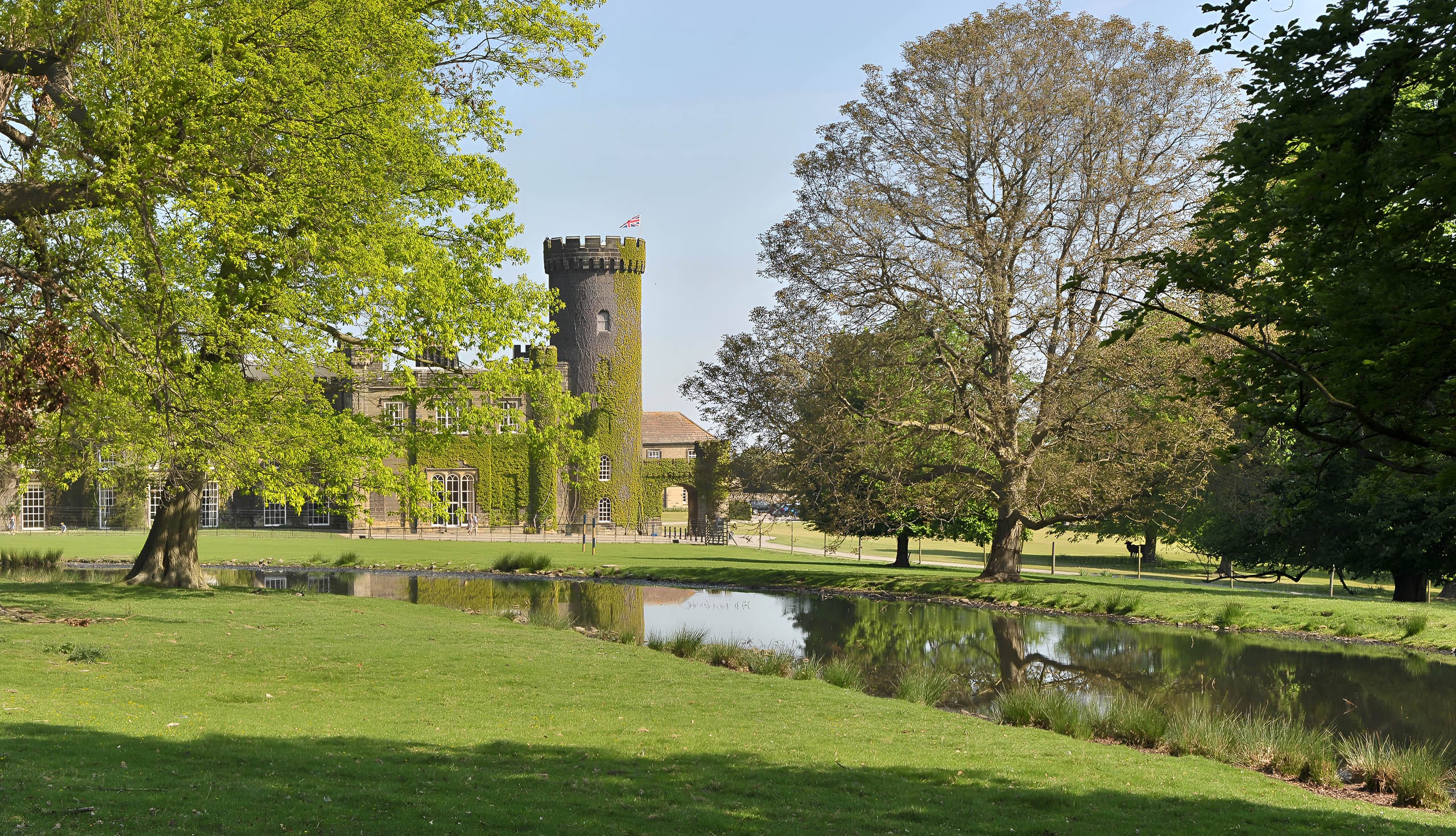 Swinton Park Hotel surrounded by lush parkland and a reflective water feature